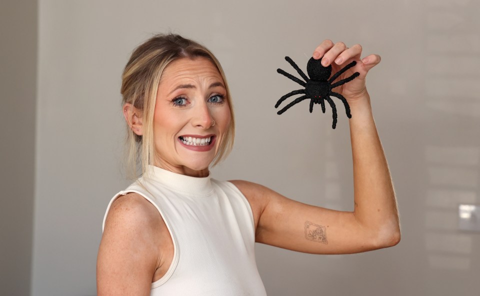 a woman is holding a fake spider in her hand