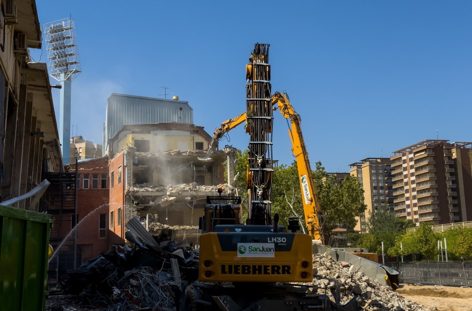 a yellow liebherr excavator is demolishing a building