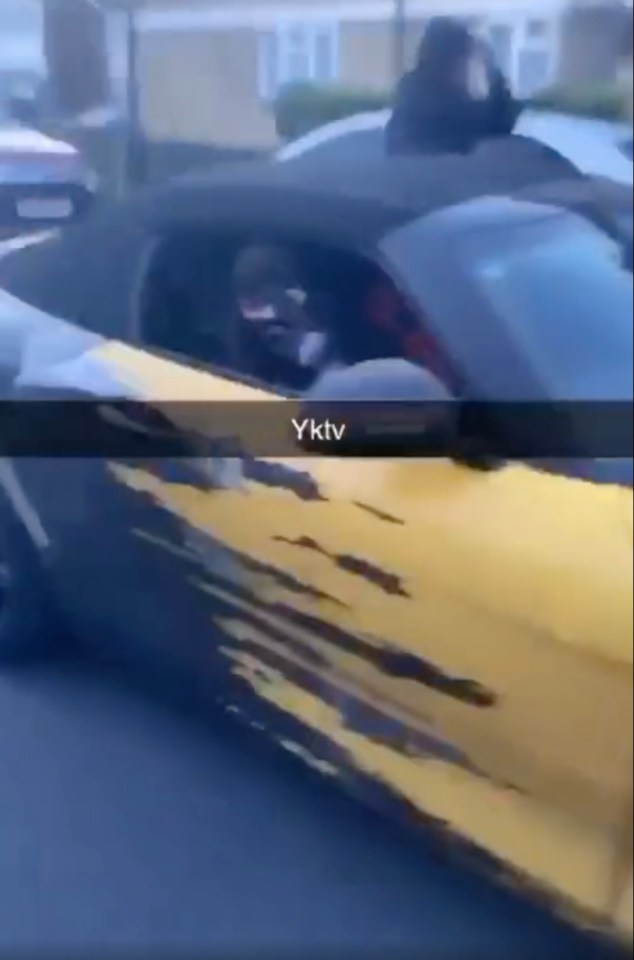 a man is driving a yellow sports car down a street .
