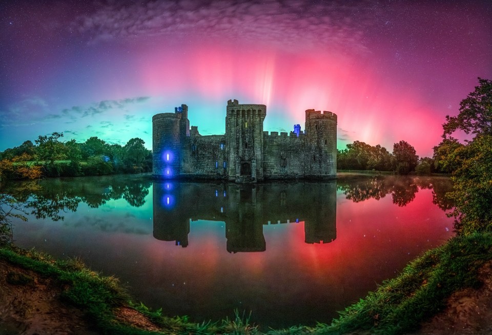 a castle in the middle of a lake with the aurora borealis behind it