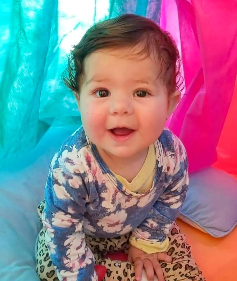 a baby wearing a sweater with clouds on it is smiling