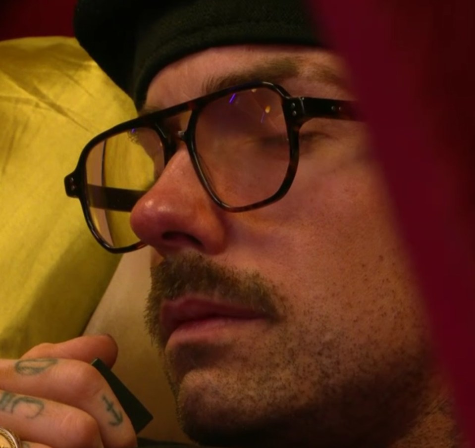 a man wearing glasses has a tattoo on his finger that says i love you