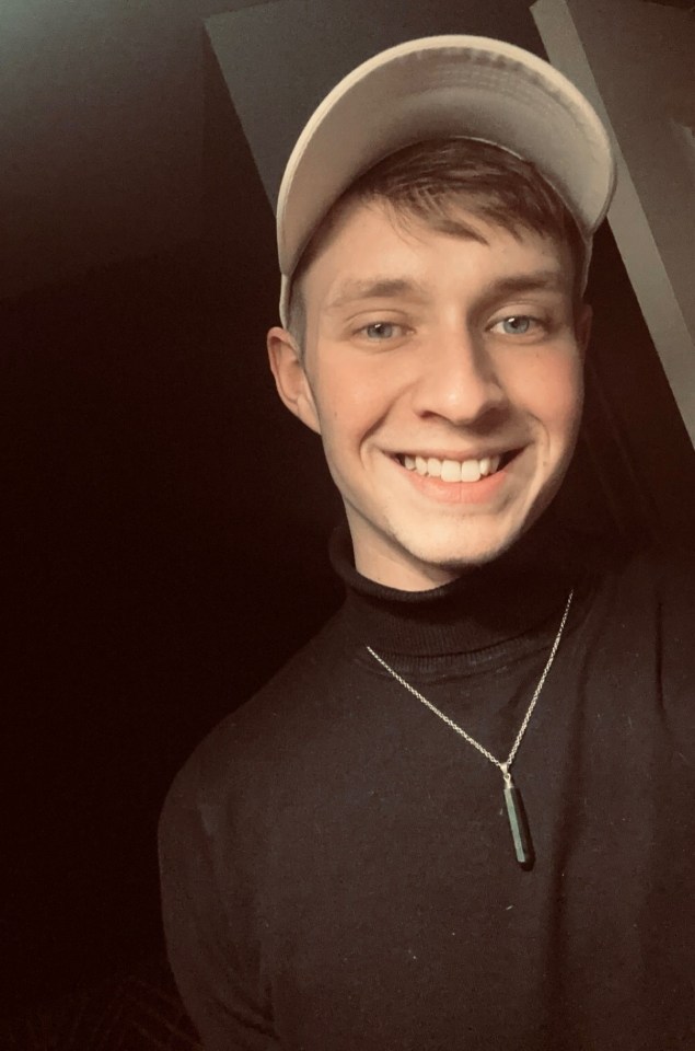 a young man wearing a hat and a necklace smiles for the camera