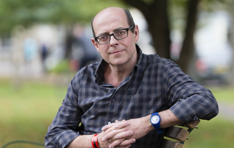 a man wearing glasses and a blue watch sits on a park bench