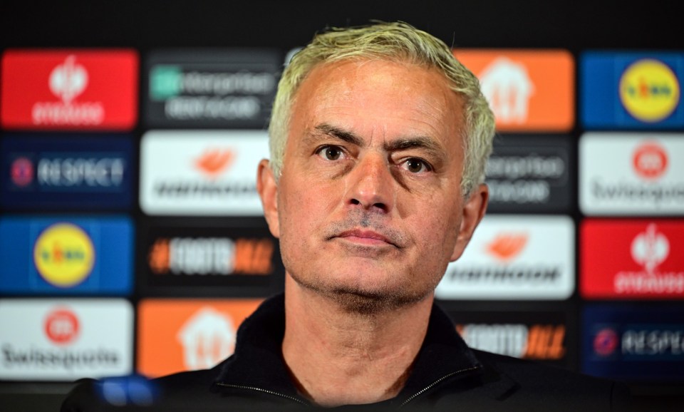 a man with a serious look on his face stands in front of a wall of advertisements