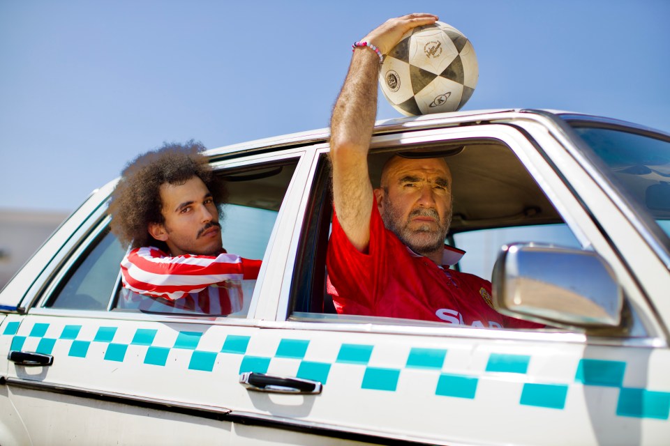 a man in a red shirt holds a soccer ball over his head
