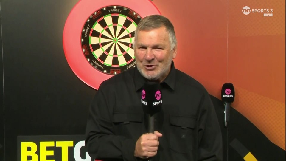 a man holding a microphone in front of a dart board that says target