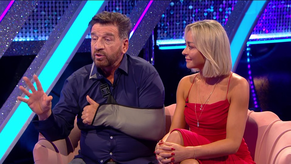 a man with a cast on his arm sits next to a woman in a red dress