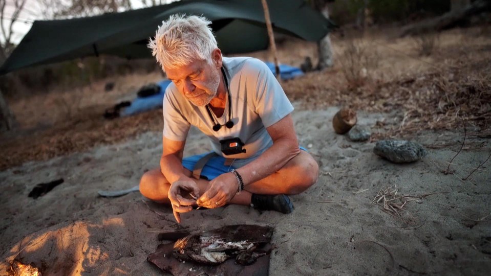 a man in a north face shirt sits in the sand