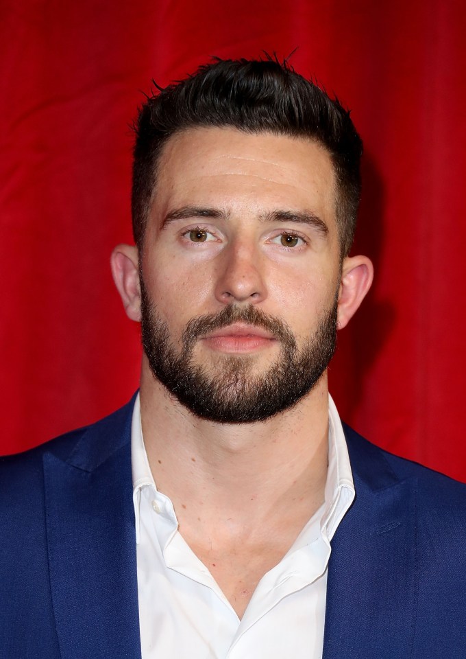 a man with a beard is wearing a blue suit and white shirt