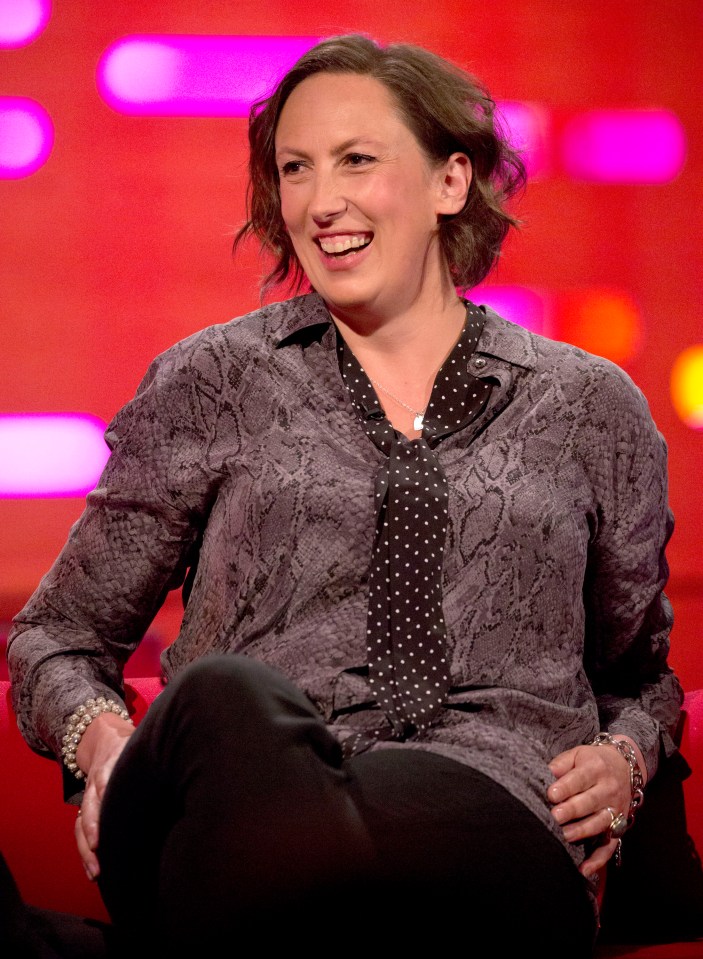 a woman wearing a snake print shirt and tie is smiling