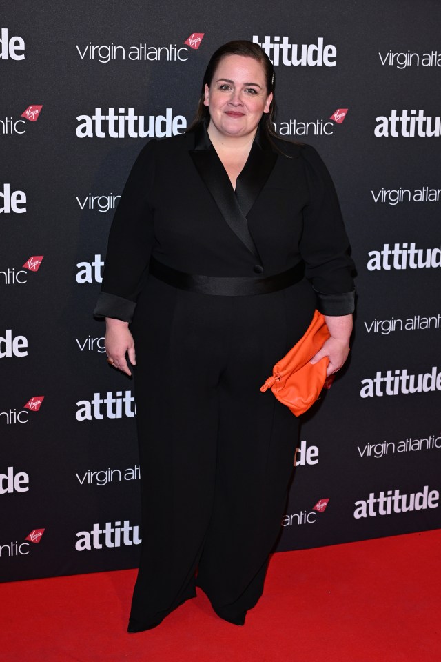 a woman stands on a red carpet at an attitude event
