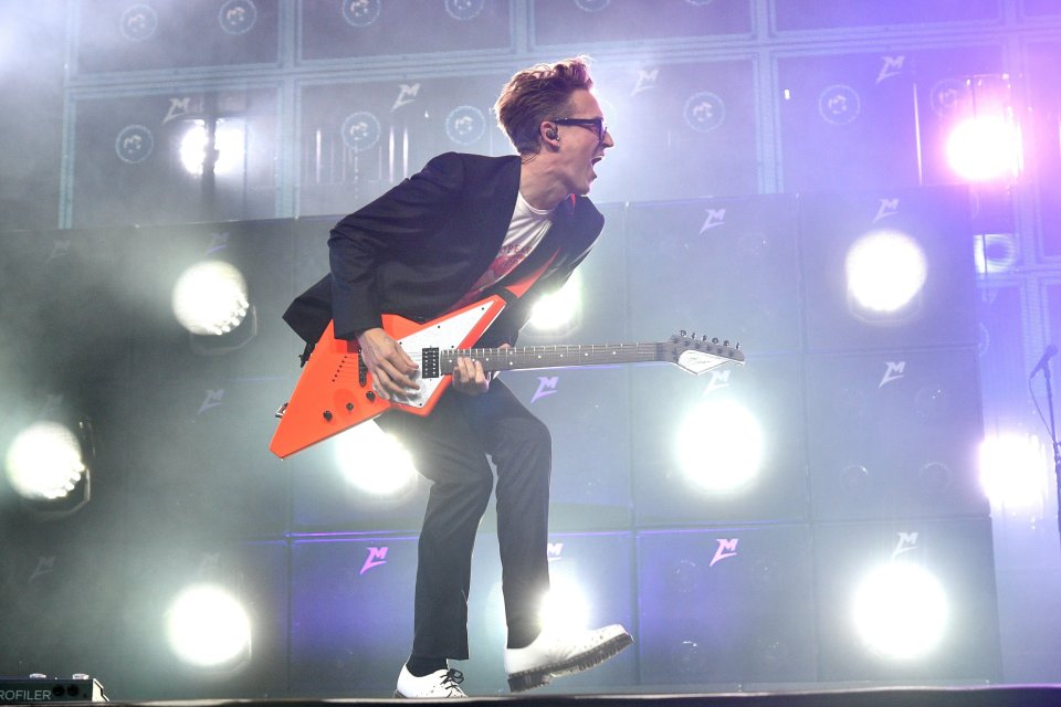 a man in a suit is playing an orange guitar