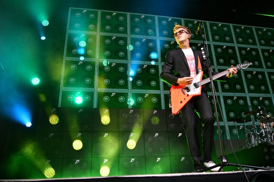 a man playing a guitar in front of a wall of speakers