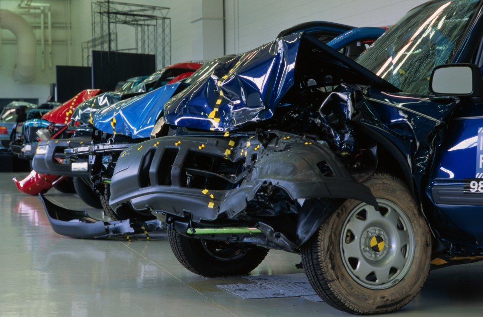 a row of damaged cars are lined up in a garage