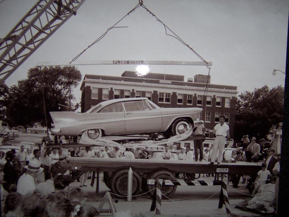 a black and white photo of a car being lifted by a crane
