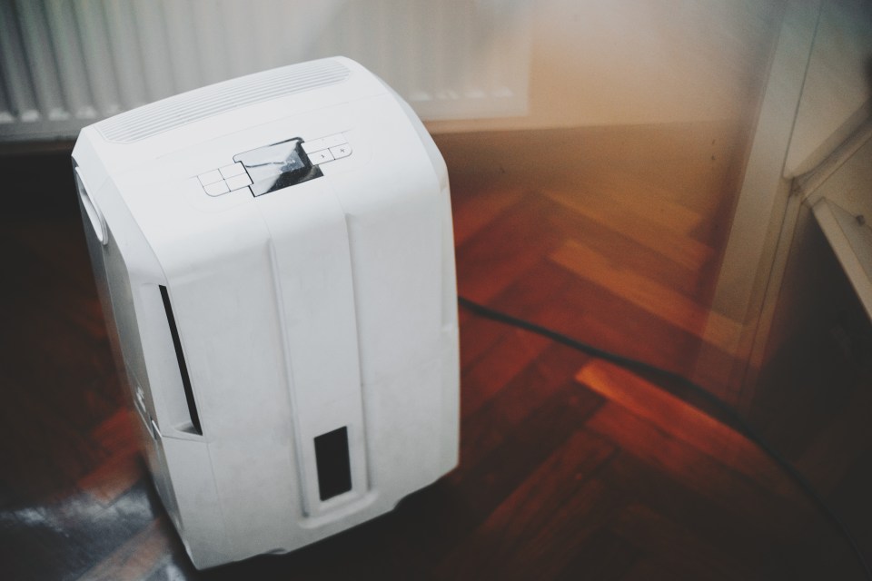 a portable air conditioner sits on a wooden floor