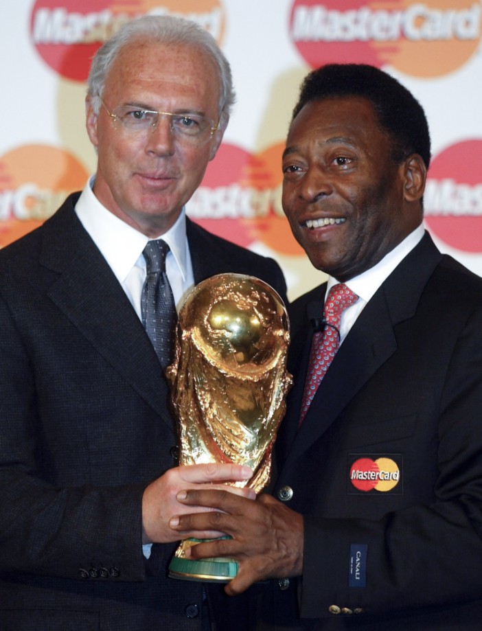FILE - Former soccer stars Franz Beckenbauer, left, from Germany and Pele, right, from Brazil, present the World Cup trophy to photographers in Berlin Wednesday, March 12, 2003. Germany's World Cup-winning coach Franz Beckenbauer has died. He was 78. Beckenbauer was one of German soccer's central figures. He captained West Germany to the World Cup title in 1974. He also coached the national side for its 1990 World Cup win against Argentina. (AP Photo/Roberto Pfeil, File)