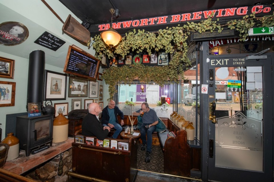three men sit in a room under a sign that says tamworth brewing co.