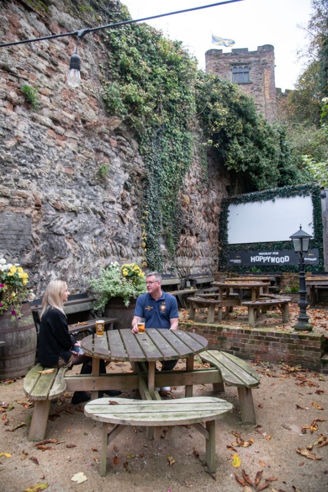 two people sit at a picnic table in front of a sign that says hoppywood