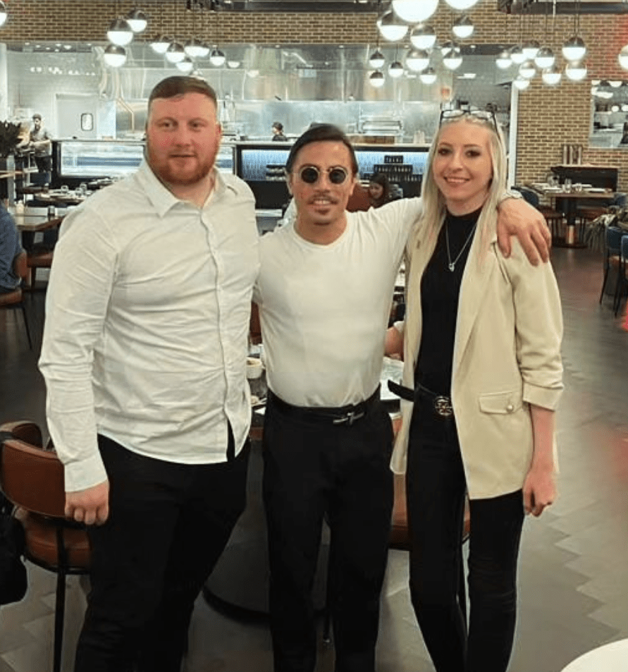 two men and a woman pose for a picture in a restaurant