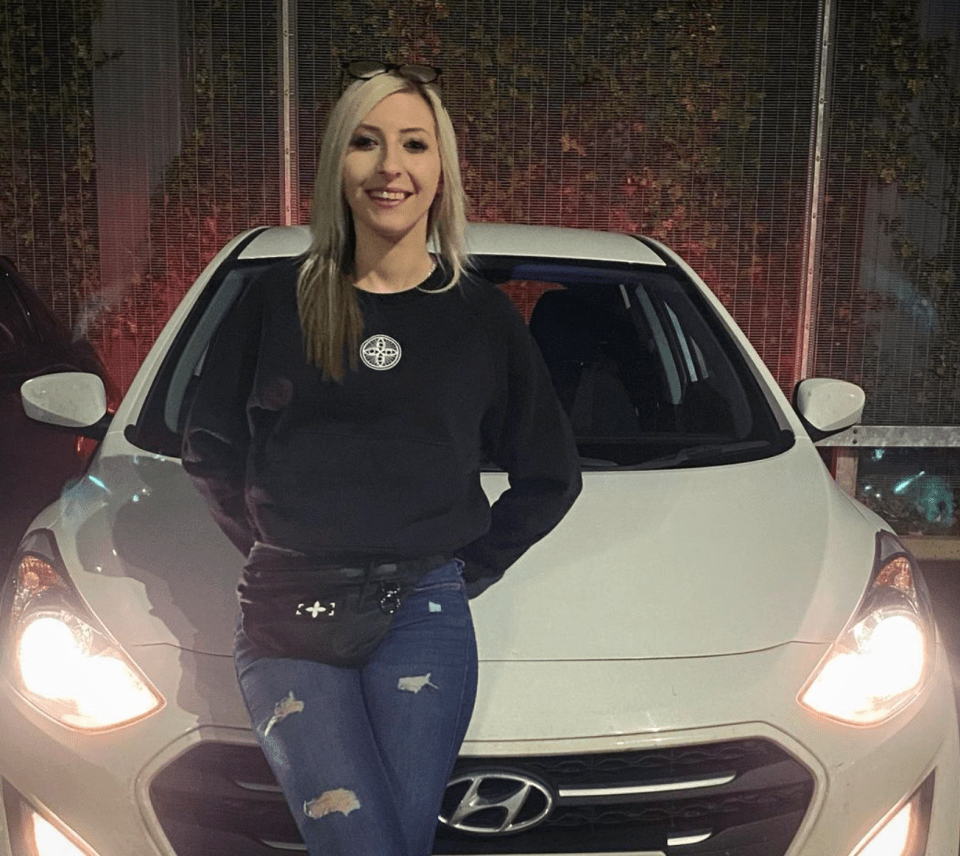 a woman stands in front of a white hyundai car