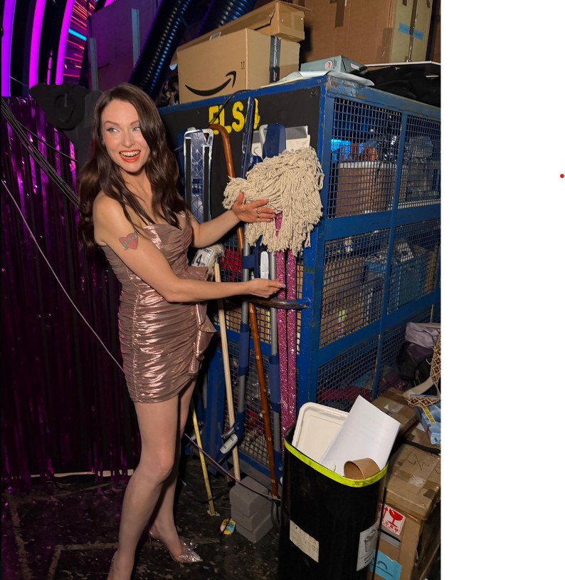 a woman holds a mop in front of a sign that says els