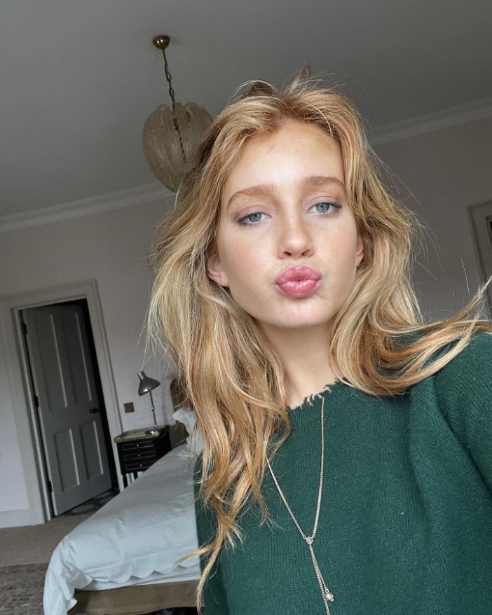 a blonde woman wearing a green sweater is making a funny face