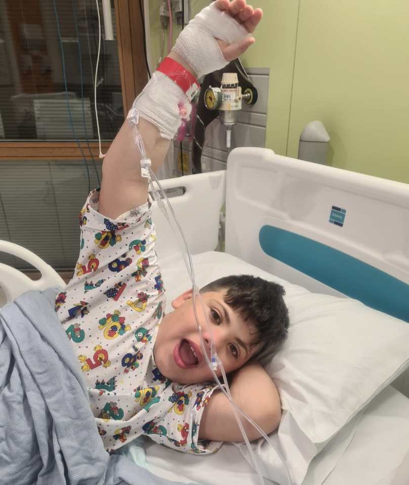 a young boy is laying in a hospital bed with his arm in the air