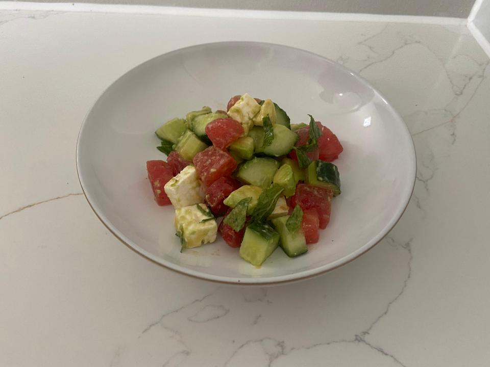 a salad with tomatoes cucumbers and feta cheese in a white bowl