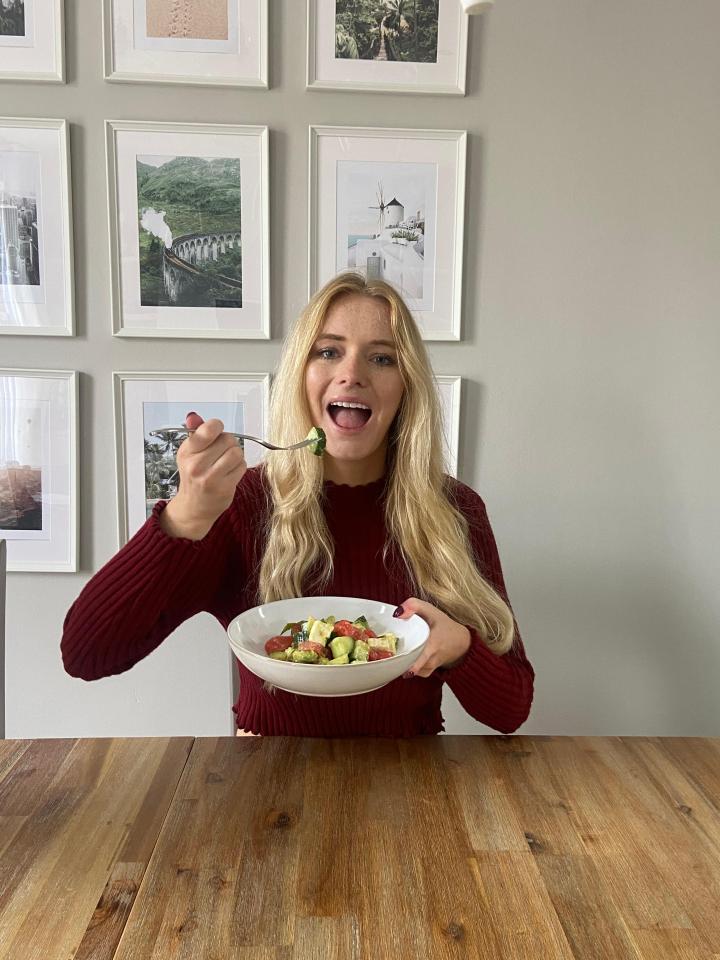 a woman in a red sweater is eating a salad with a fork