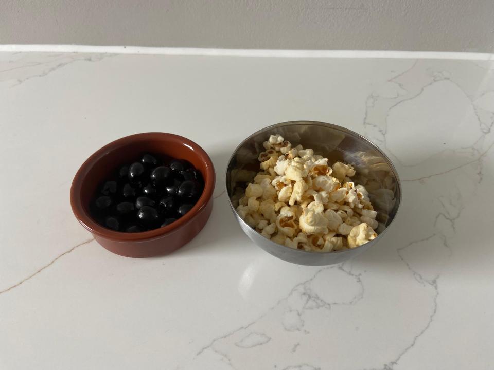 a bowl of blueberries next to a bowl of popcorn