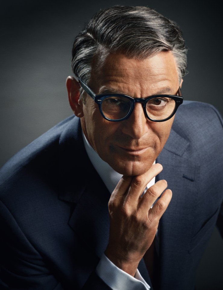 a man in a suit and glasses has his hand on his chin