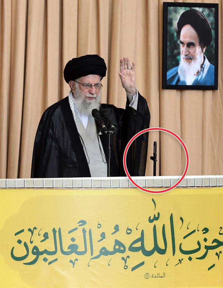 a man stands at a podium in front of a yellow sign with arabic writing on it