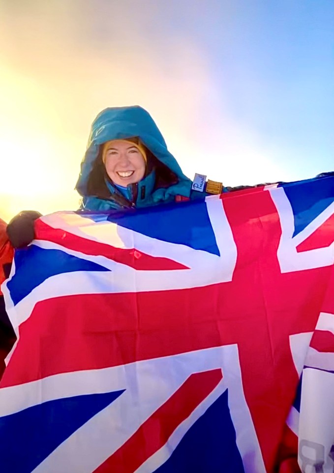 a woman in a blue jacket is holding a british flag