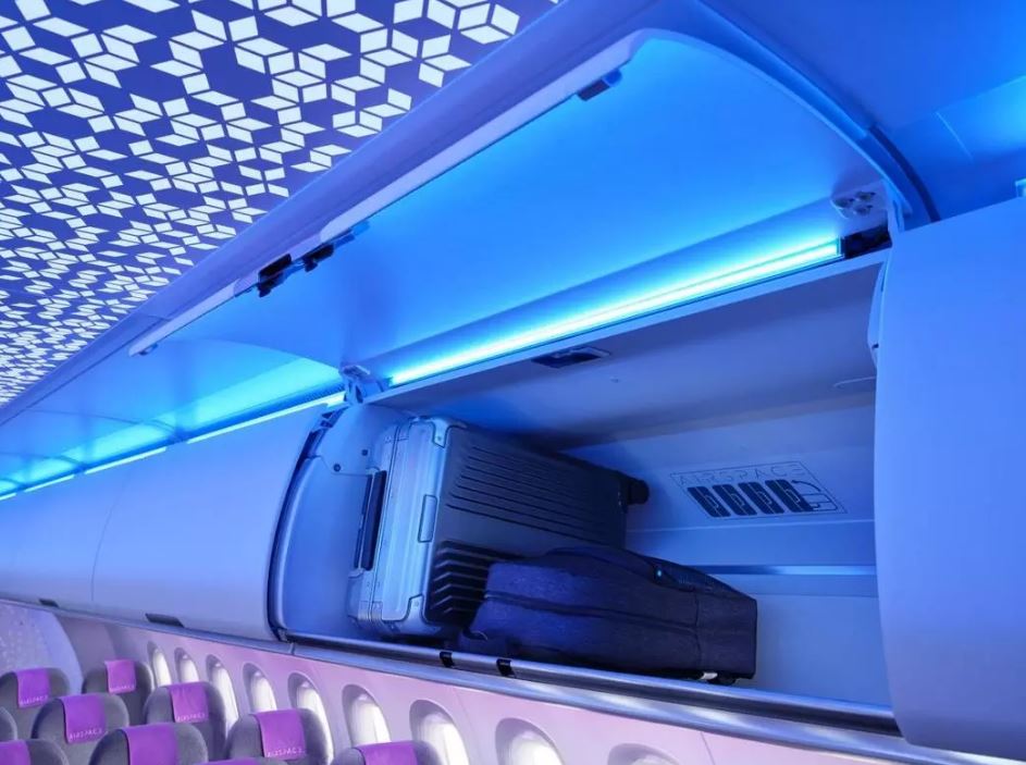 a luggage compartment on an airplane with purple seats