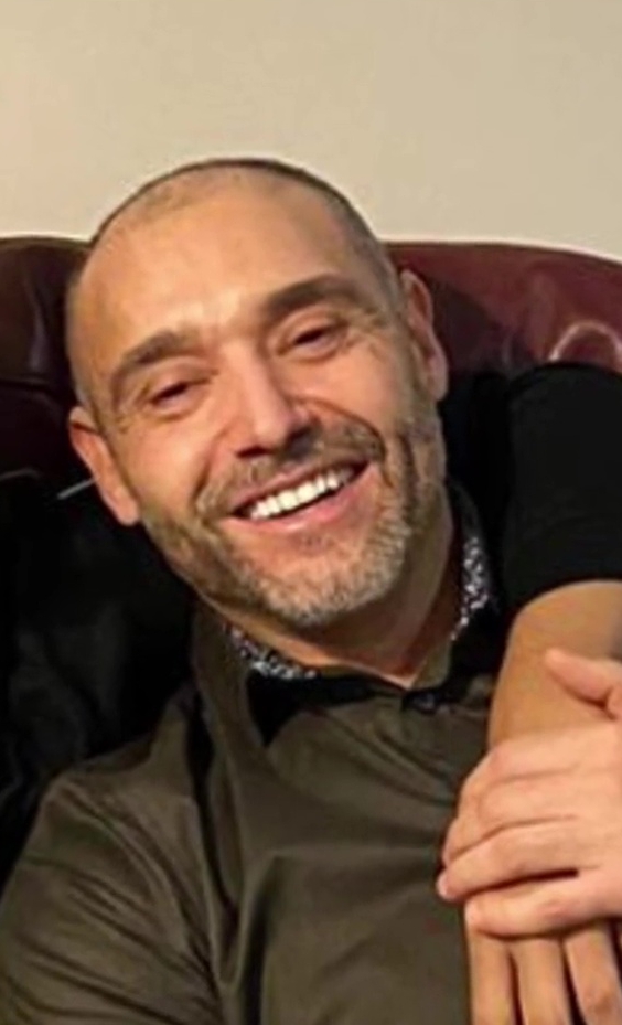 a man with a beard is smiling while sitting on a couch .