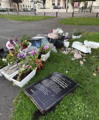 a plaque in the grass says the memorial of all children