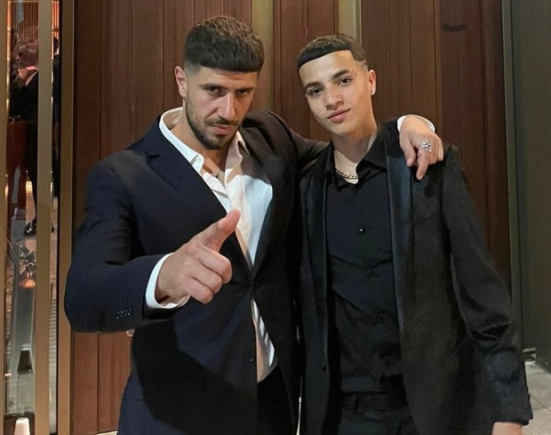 two men are posing for a picture and one has a ring on his finger