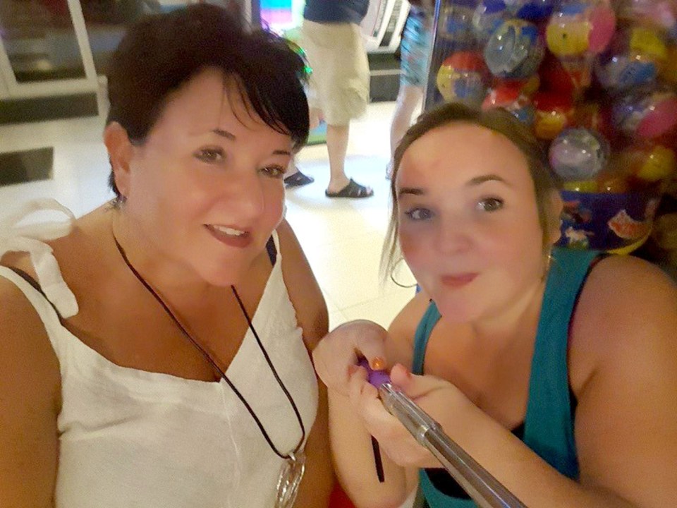 two women are posing for a picture in front of a vending machine that says bubblegum