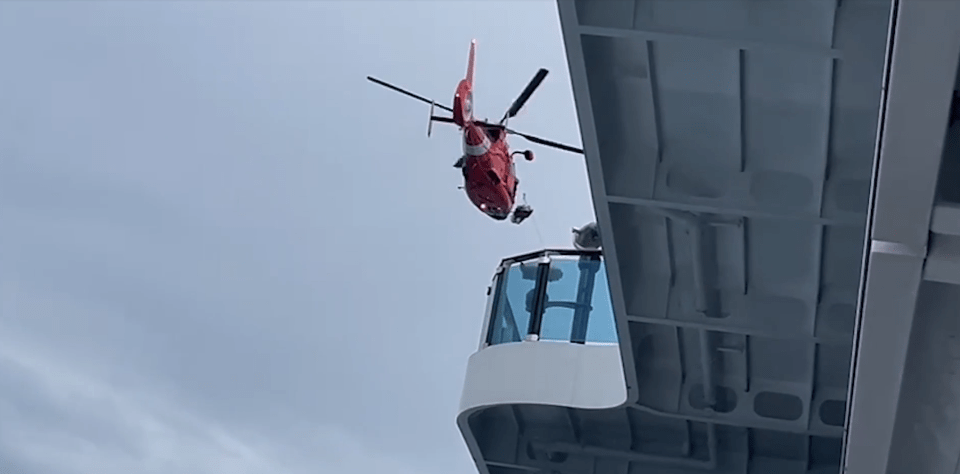 a red helicopter is flying over a building with the letter h on it