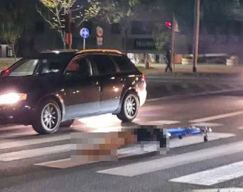 a person is laying on a stretcher on the side of the road next to a car .