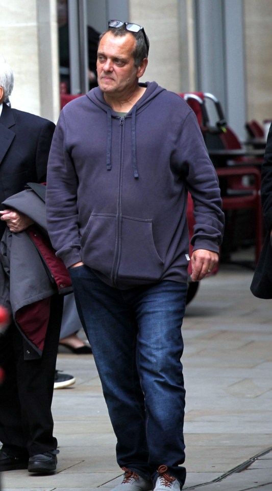 a man wearing a grey hoodie and jeans walks down a sidewalk
