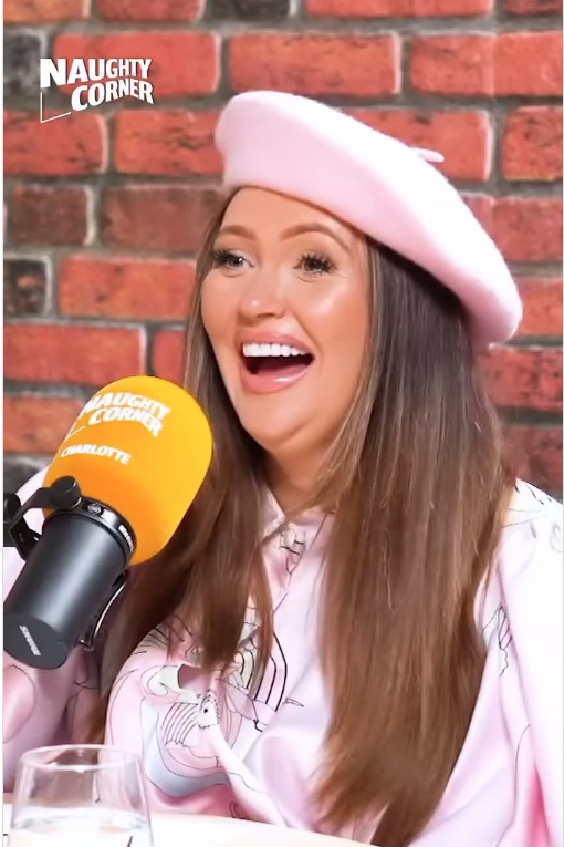 a woman wearing a pink beret is smiling in front of a naughty corner microphone