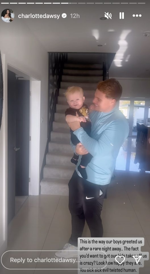a man is holding a baby in his arms and a reply to charlottedawsy is below him
