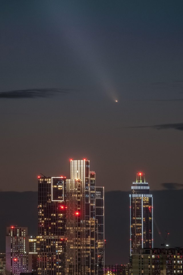 a city skyline at night with a comet flying in the sky