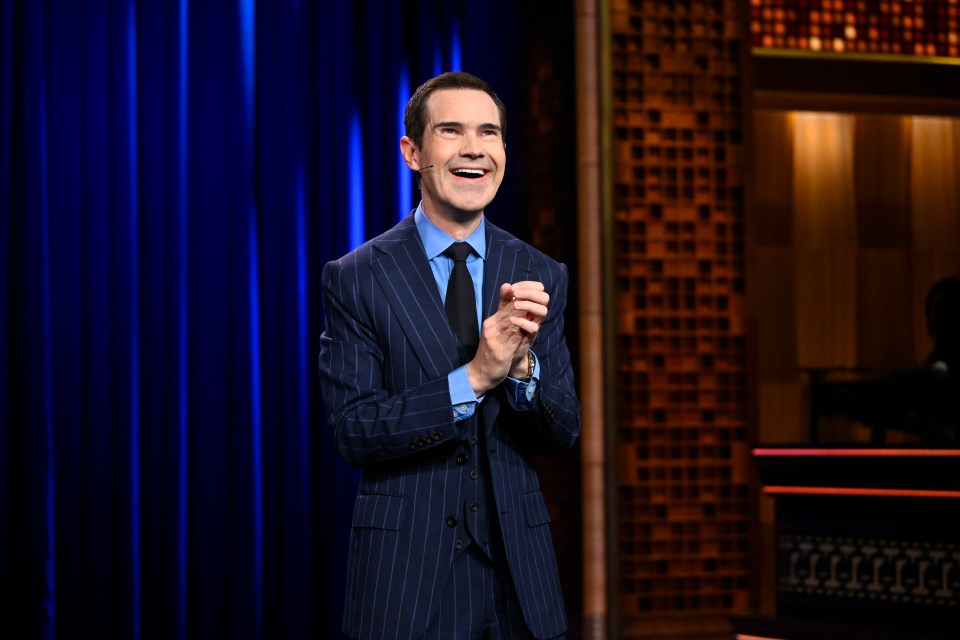 a man in a suit and tie is clapping his hands