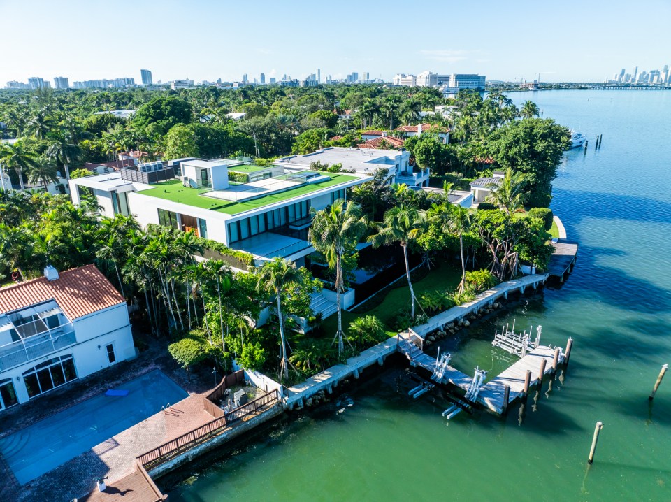 a large house with a green roof sits next to a body of water