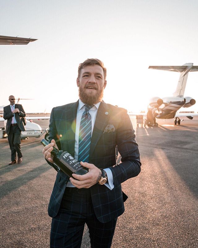 a man in a suit is holding a bottle of pinot noir
