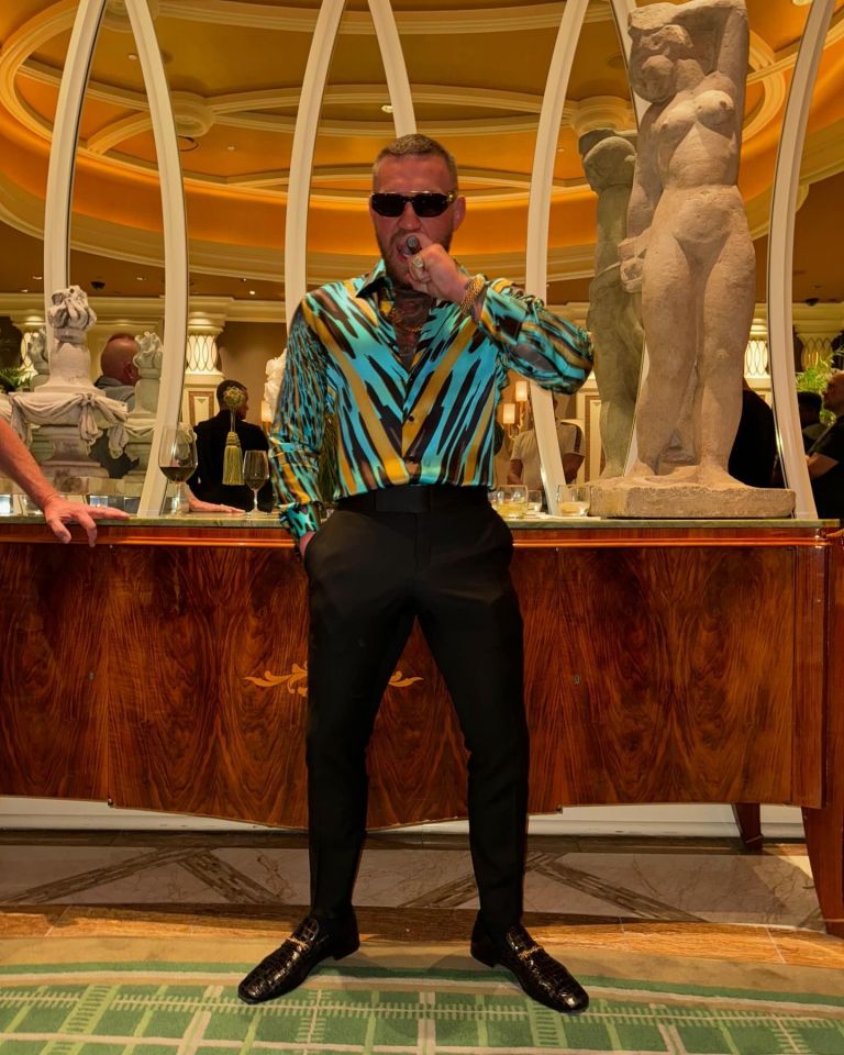 a man wearing sunglasses stands in front of a statue of a woman